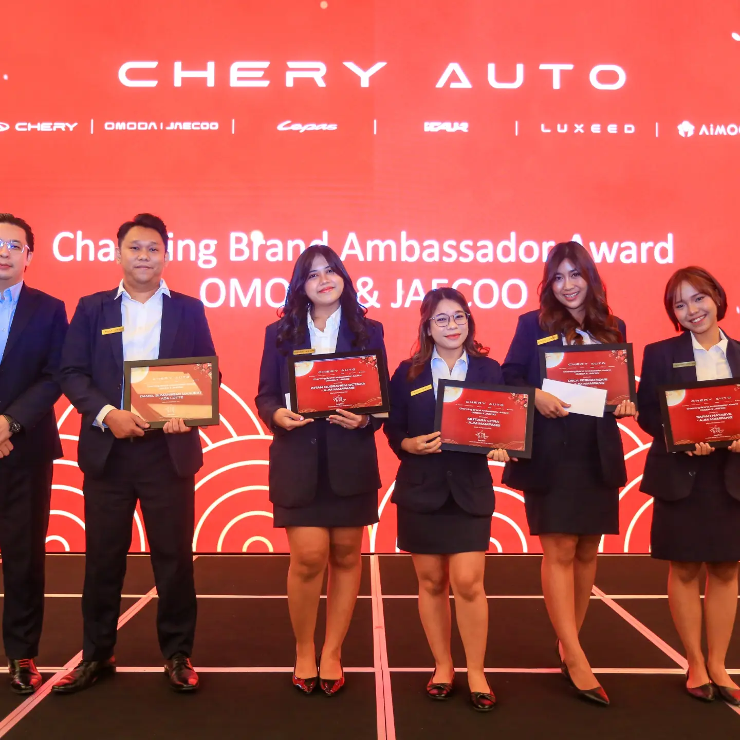 Potret para penerima piagam dengan latar Charming Brand Ambassador Award OMODA & JAECOO